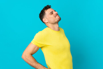 Young caucasian handsome man isolated on blue background suffering from backache for having made an...