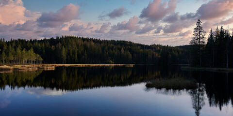 Fototapeta premium Sunrise over the lake. The sky is dramatic and on fire. Shot in Nordmarka, Oslo, Norway. 