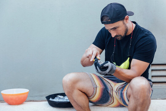Man opening oyster shells while sitting in backyard