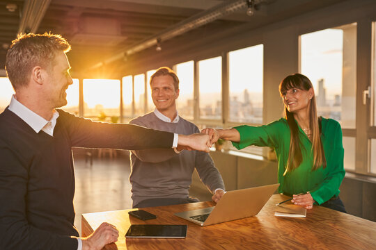 Mature colleagues giving fist bumps to each other in meeting