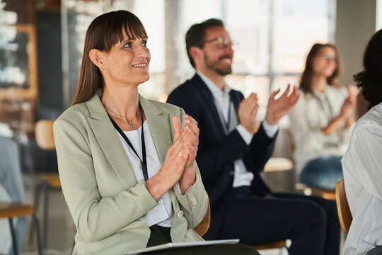 Businesswoman clapping hands with colleagues in conference centre