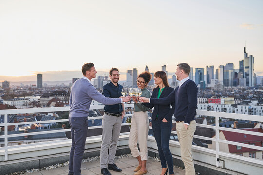 Entrepreneurs toasting wine glasses while standing on rooftop