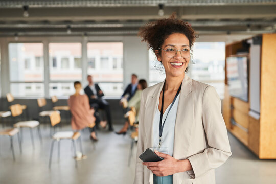 Smiling Businesswoman With Mobile Phone Looking Away At Office