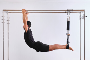 Man doing stretching exercise while practicing pilates on trapeze table