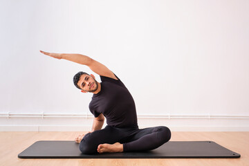 Handsome man doing stretching exercise on mat in exercise room