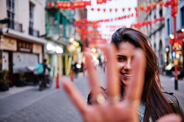 Smiling woman showing palm while standing on street in city