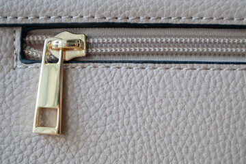 Natural or artificial leather texture. Fragment of a beige or powdery bag with a zipper and...