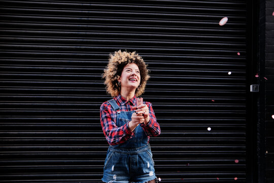 Cheerful woman looking at confetti falling in front of shutter