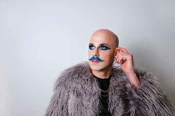 Thoughtful man with make up looking away against white background