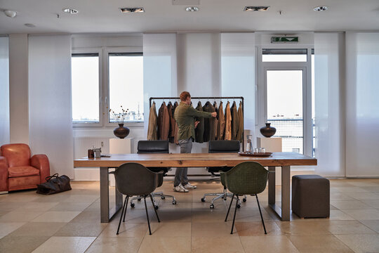 Male customer looking clothes hanging on rack at clothing studio