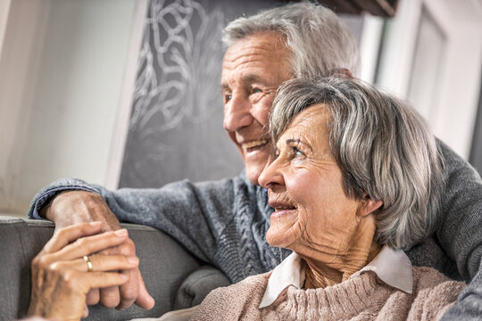 Senior wife holding hand of husband in living room