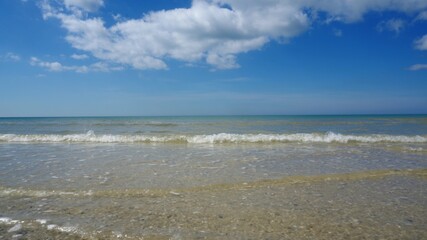 A beautiful seashore or ocean, majestic clouds in the blue sky, clear and transparent water on a sunny day. A place of rest and relaxation.