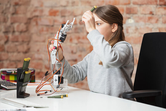 Girl holding robotic arm and work tool at table