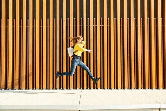 Woman checking time while running over footpath