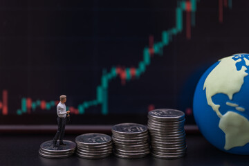Business Money, Financial and Home Concept. Businessman miniature figure people walking on top of stack of silver coins with mini world ball and  candlestick chart as background.