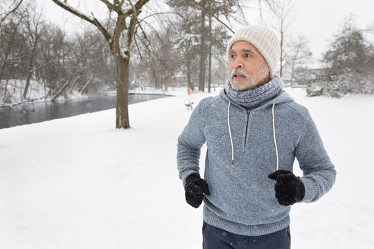 Senior Man Looking Away While Running At Park During Winter