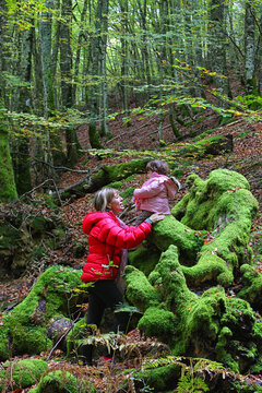 Mother talking with daughter sitting on moss covered rocks in Gorbea Natural Park