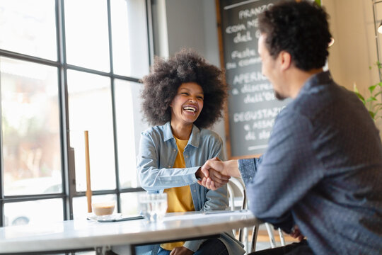 Male customer doing handshake with businesswoman after meeting in cafe