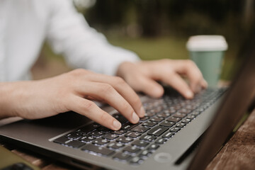 Man typing on keyboard outside. Freelancer working from distance.