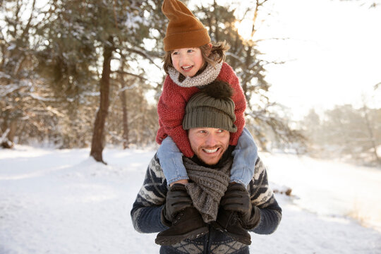 Smiling father looking away while carrying son on shoulder during winter