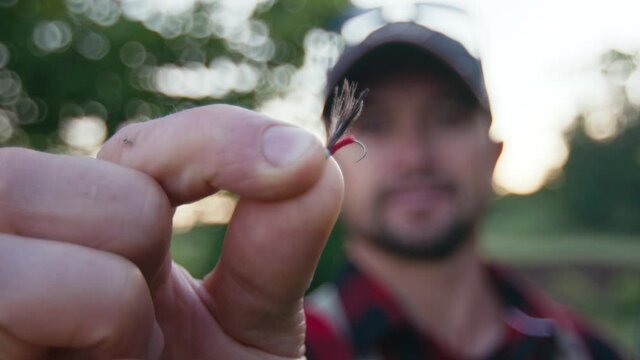 Fly fishing, close up fly details,. Angler stands outdoor and shows his tiny dry fly made with CDC feathers