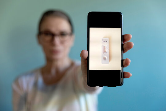 Woman showing photograph of corona rapid test kit on mobile phone
