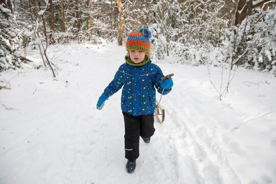 Cute Boy Pulling Sled On Snow During Winter