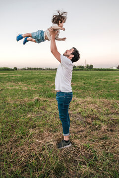 Playful man playing with baby boy while standing on grass