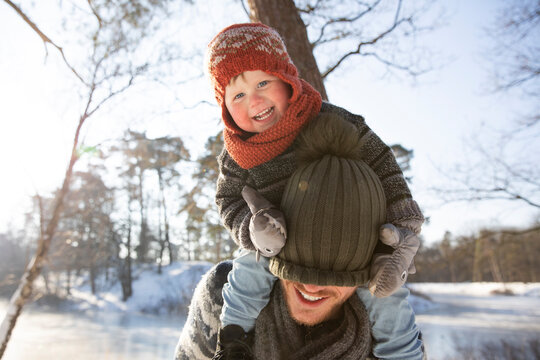 Smiling son pulling knit hat over father's face during winter