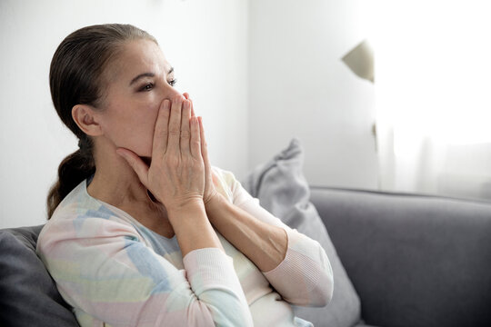 Mature woman looking away while sitting on sofa