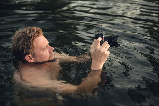Man swimming in lake, take pictures with his camera