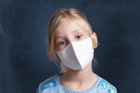 Girl with cocked head wearing protective face mask against black background