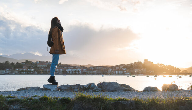 Spain, Cantabria, San Vicente de la Barquera, Young backpacker tourist enjoying sea coast at sunset
