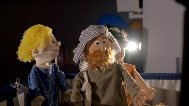 Three puppet dolls hiding under the scenes during the performance in puppet theater. Two puppet men with beard and in typical Asian clothing