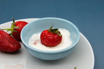 Red ripe fresh strawberries were dipped in a bowl of sugar