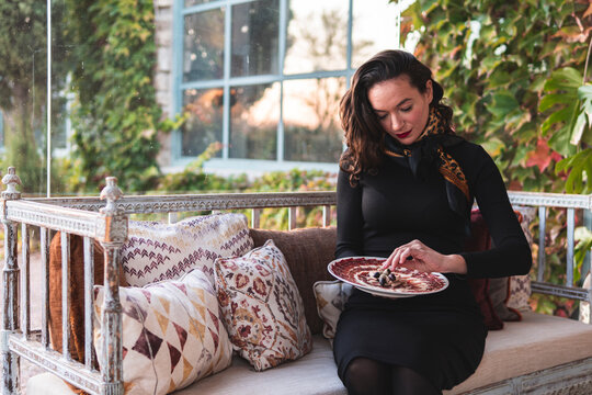 Female owner garnishing red meat plate while sitting in restaurant