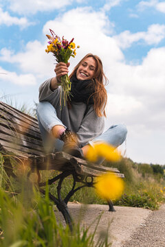 Smiling woman sitting on bench in nature