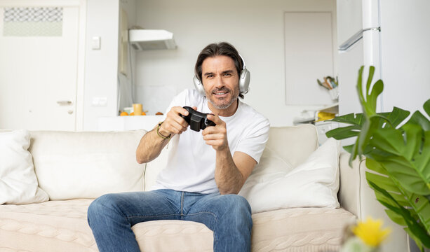 Excited man playing video game while sitting on sofa in living room