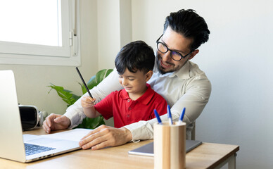 Businessman looking at laptop while sitting with son at home