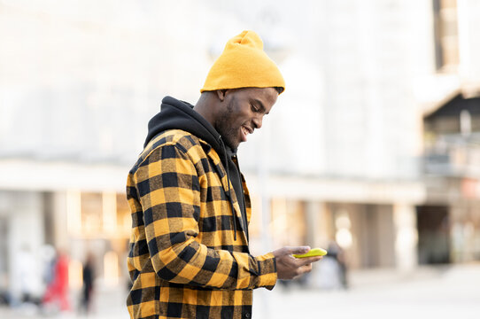 Young man wearing knit hat while using smart phone