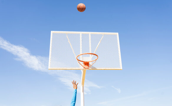 Sportswoman playing basketball below sky