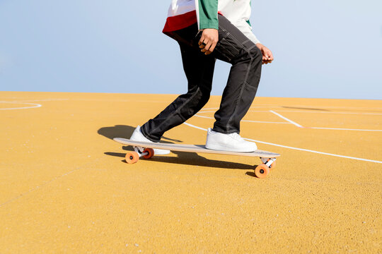 Young man riding skateboard on sports court