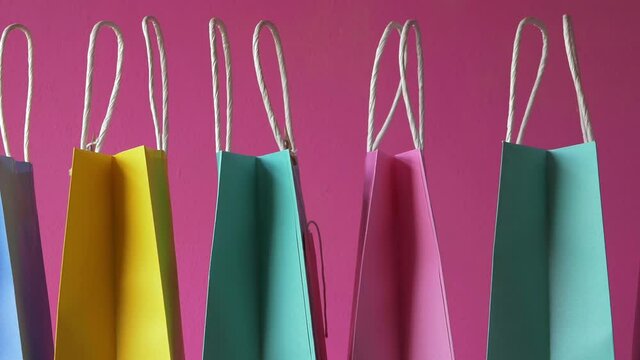 Row of colorful gift bags on pink background medium shot