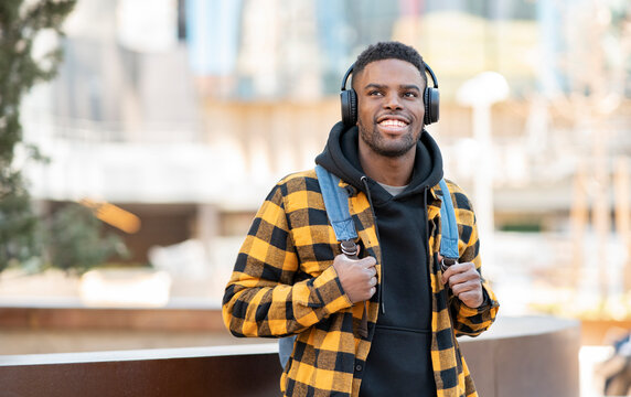Smiling man wearing checked yellow jacket listening music through headphones