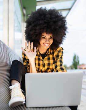African woman waving during video call on laptop