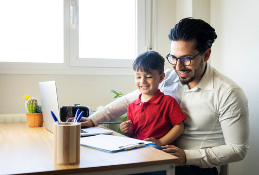 Businessman and son smiling while looking at clipboard at home