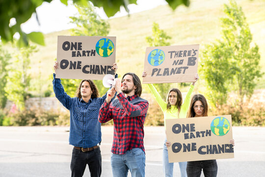 Male and female protestors with poster alerting on climate change at footpath