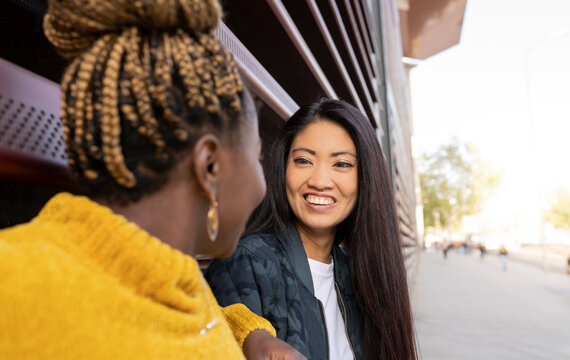 Woman with long hair talking to female friend outdoors