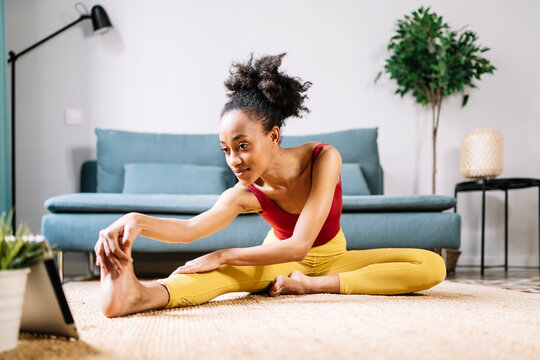 Young woman exercising while watching online tutorial on digital tablet at home