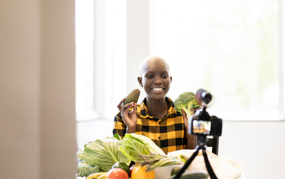 Female influencer with vegetables vlogging at home